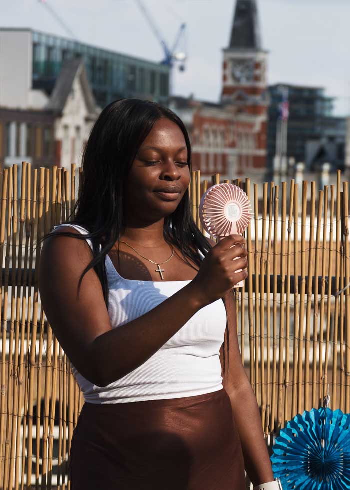 Employee cooling herself down with a handheld fan